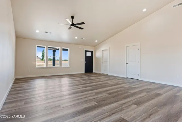 a view of an empty room with window and wooden floor