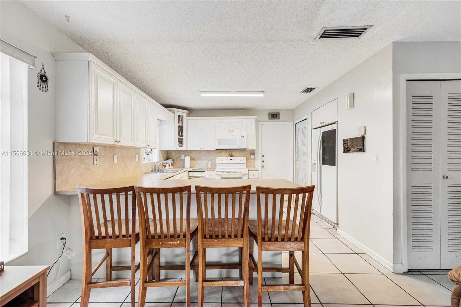 13202 Southwest 12th Lane Miami, FL 33184 - Photo 15 of 47 a kitchen with a dining table chairs and white cabinets