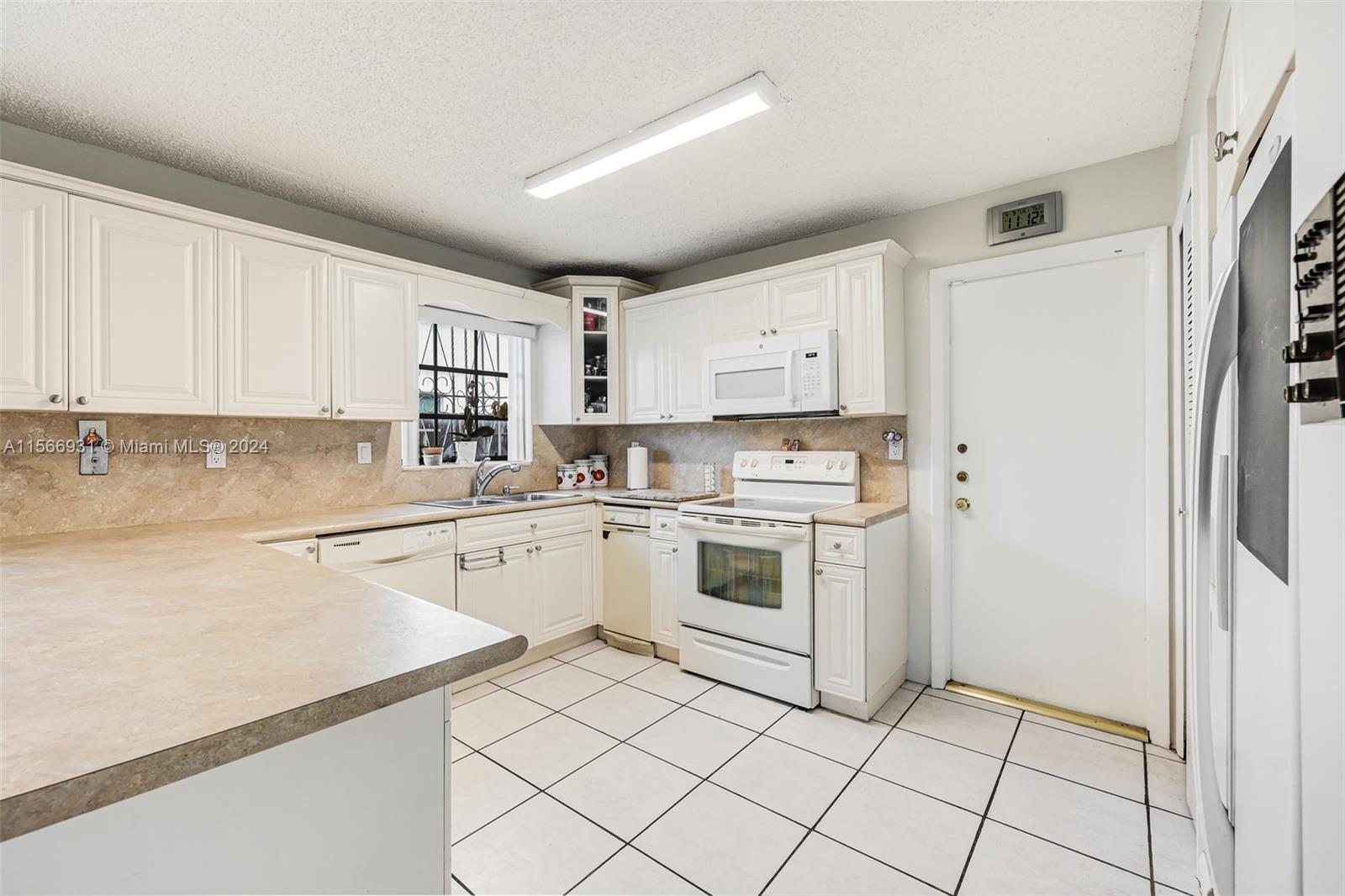 13202 Southwest 12th Lane Miami, FL 33184 - Photo 16 of 47 a kitchen with white cabinets a sink and white appliances