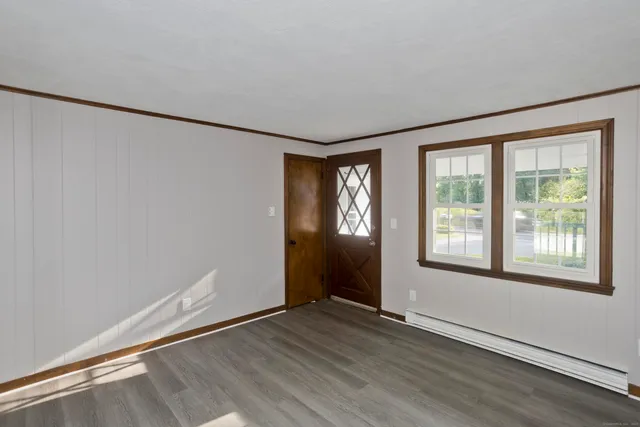 an empty room with wooden floor and windows
