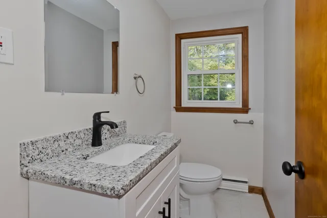 a bathroom with a granite countertop sink toilet and mirror