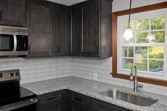 a kitchen with granite countertop a sink a stove and cabinets