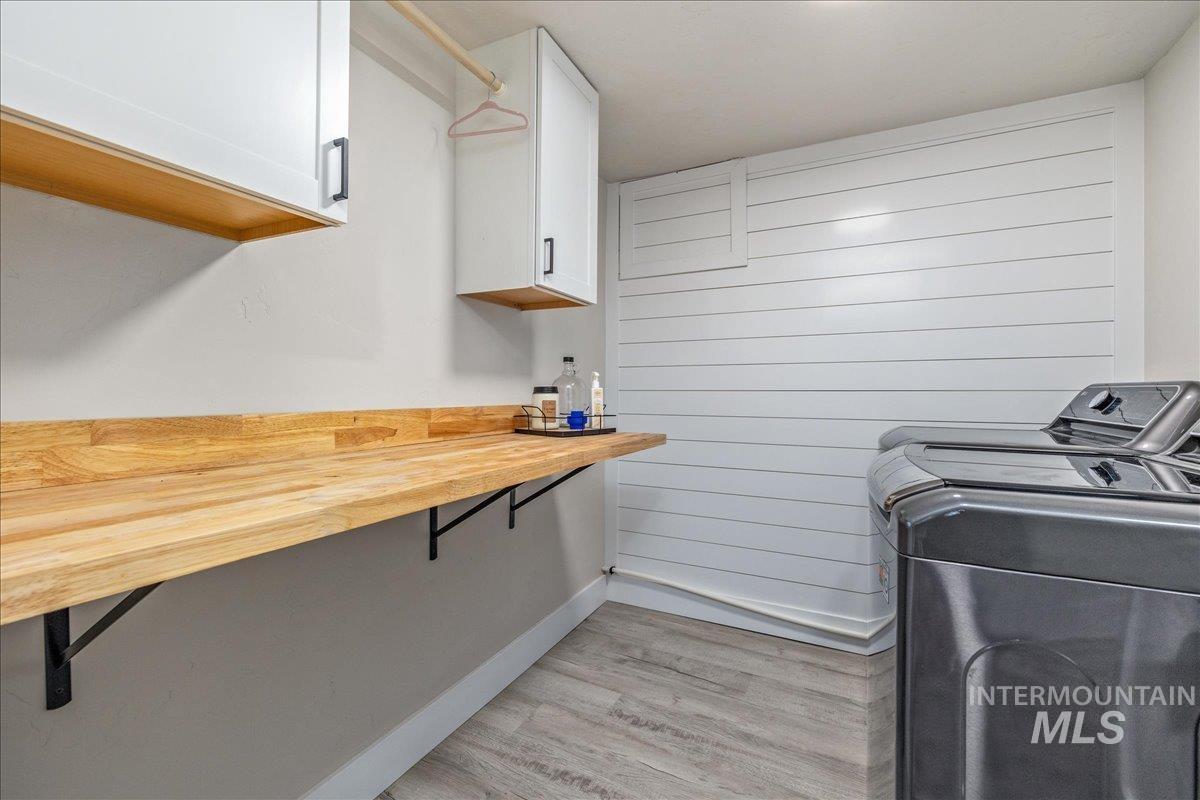 23011 Allendale Road Parma, ID 83660 - Photo 34 of 50 Wood-finish countertop, white upper cabinetry with black hardware, white shiplap wall accent, and wood-finish flooring
