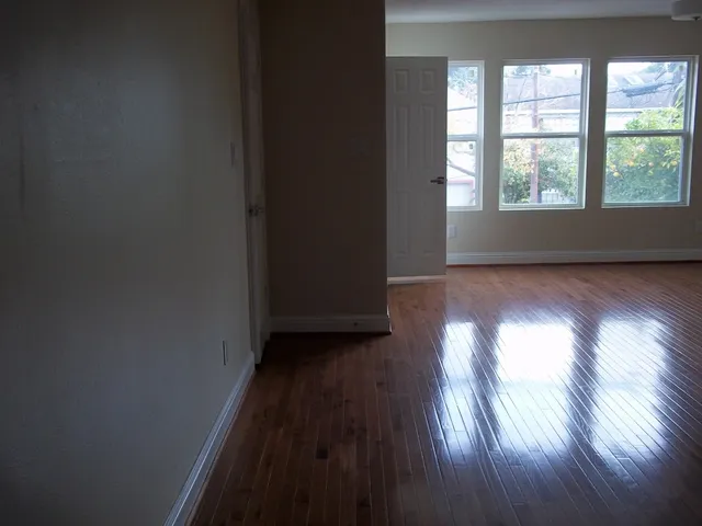 a view of an empty room and wooden floor and window