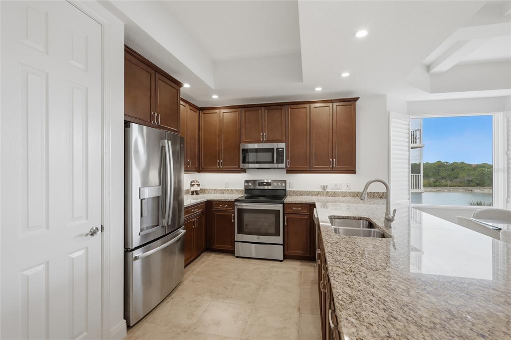 10520 Boardwalk Loop, Unit 301 Bradenton, FL 34202 - Photo 11 of 55 a kitchen with stainless steel appliances granite countertop a refrigerator a stove and a sink with wooden cabinets