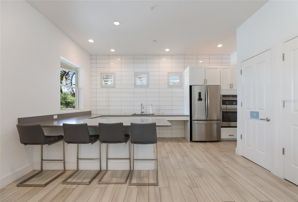 10520 Boardwalk Loop, Unit 301 Bradenton, FL 34202 - Photo 44 of 55 a kitchen with stainless steel appliances granite countertop a refrigerator a sink a stove a dining table and chairs with wooden floor