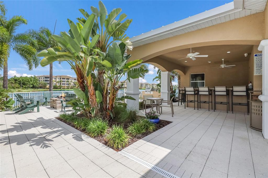 10520 Boardwalk Loop, Unit 301 Bradenton, FL 34202 - Photo 48 of 55 a view of a patio with table and chairs potted plants and palm trees