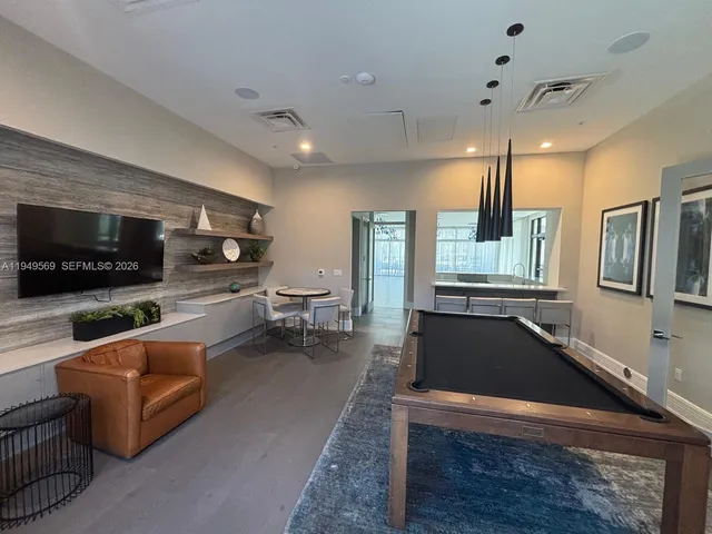 a living room with furniture a flat screen tv and kitchen view
