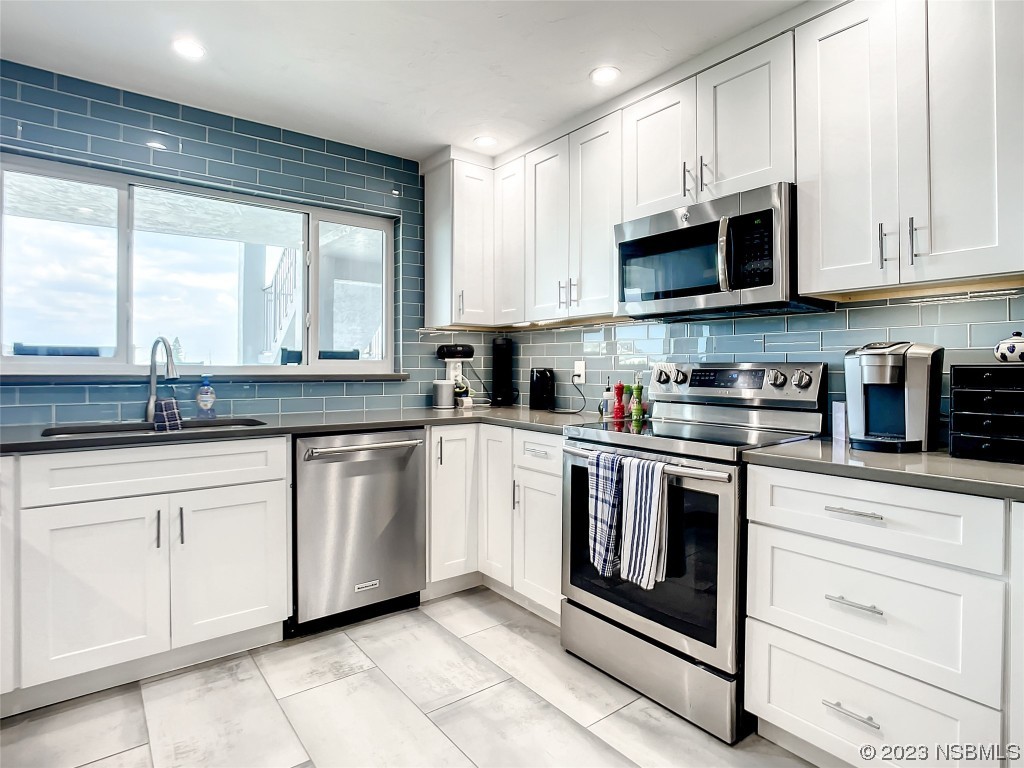 6584 Engram Road, Unit D302 New Smyrna Beach, FL 32169 - Photo 20 of 39 a kitchen with stainless steel appliances granite countertop a stove a sink and white cabinets