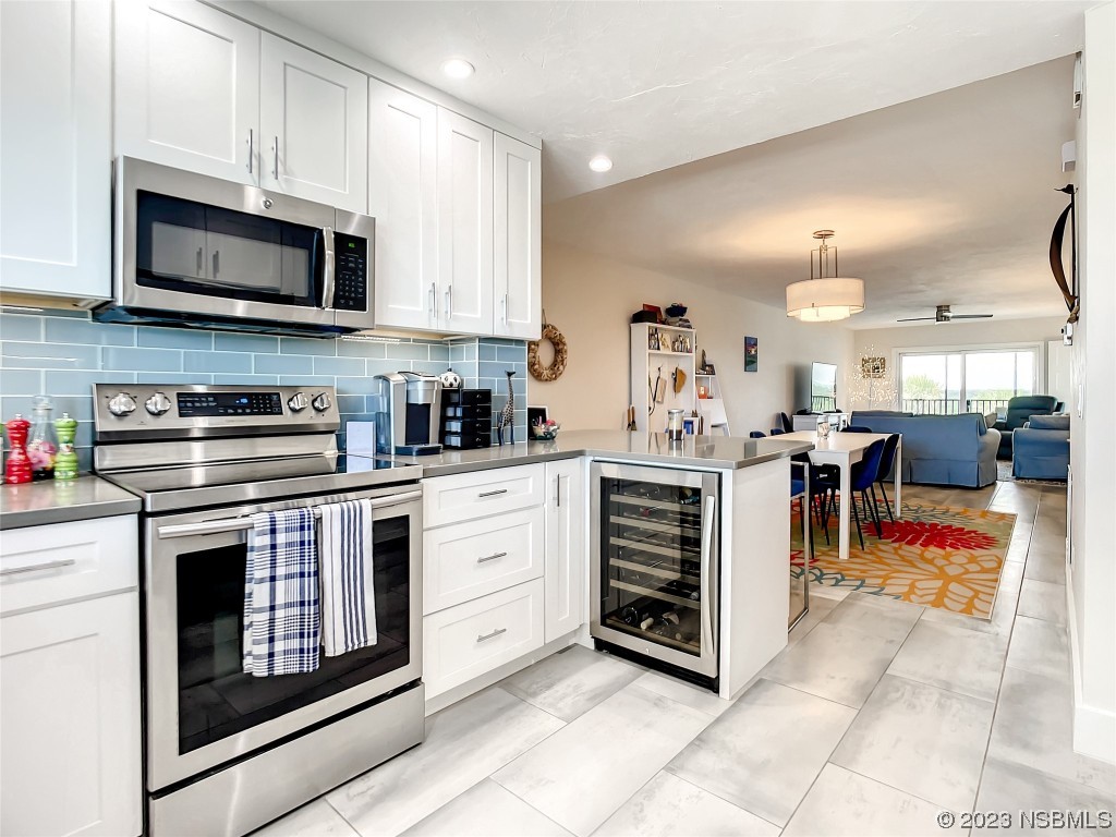 6584 Engram Road, Unit D302 New Smyrna Beach, FL 32169 - Photo 21 of 39 a kitchen with stainless steel appliances kitchen island granite countertop a stove a sink and a microwave