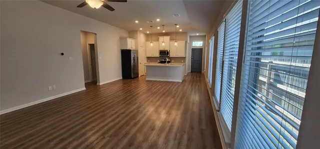 a view of a hallway with wooden floor and a kitchen