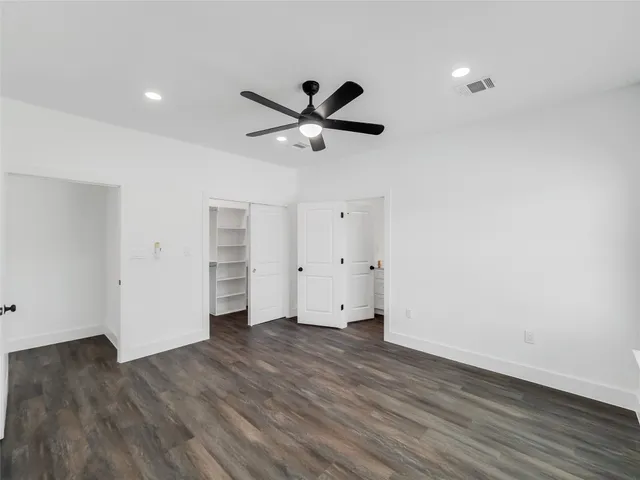 an empty room with wooden floor and a ceiling fan
