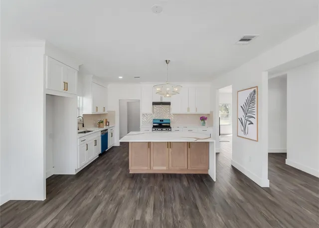 a kitchen with stainless steel appliances a stove top oven a sink and a refrigerator