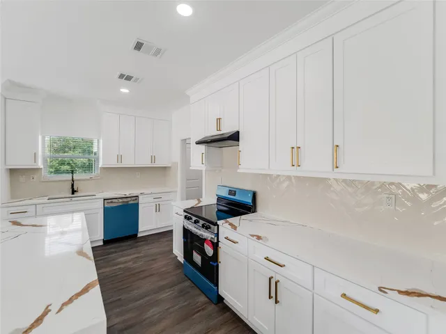 a kitchen with granite countertop a sink a stove and cabinets