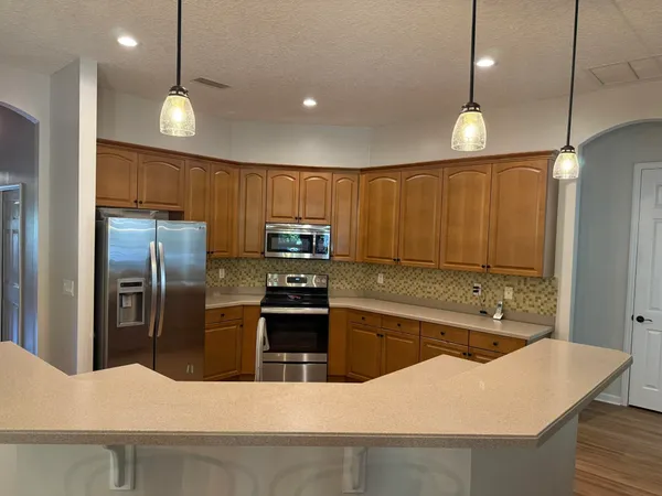 a living room with furniture kitchen area and a chandelier
