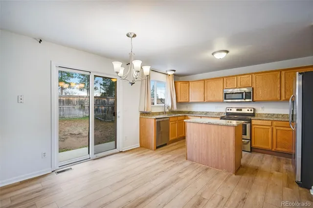 a kitchen with granite countertop a stove top oven a sink dishwasher a dining table and chairs with wooden floor