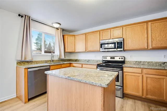 a kitchen with granite countertop a sink cabinets stainless steel appliances and a window