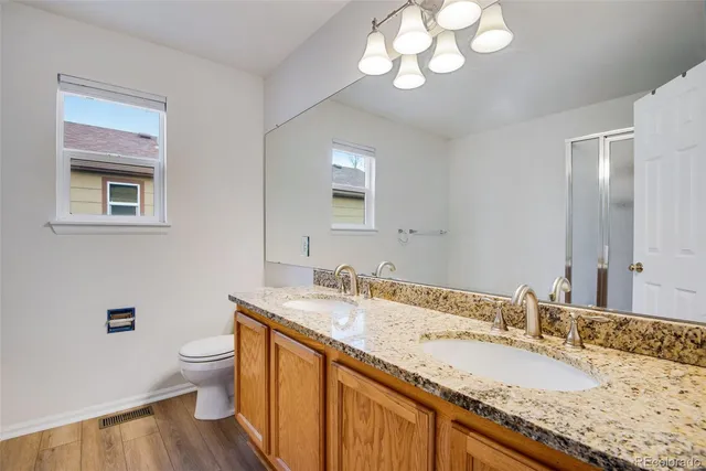 a bathroom with a granite countertop sink a toilet and a mirror