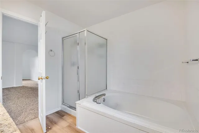 a bathroom with a tub a mirror and a shower