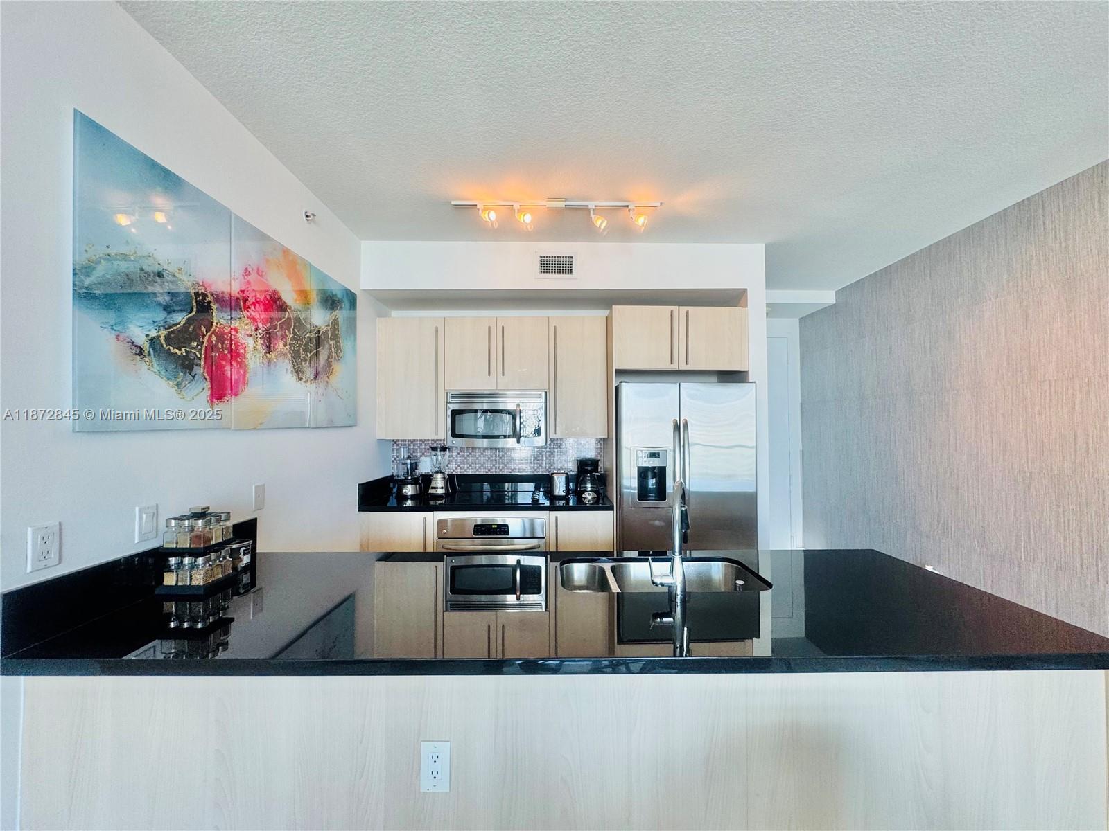 79 Southwest 12th Street, Unit 3211S Miami, FL 33130 - Photo 7 of 32 a kitchen with stainless steel appliances a stove a refrigerator a sink a counter space and cabinets