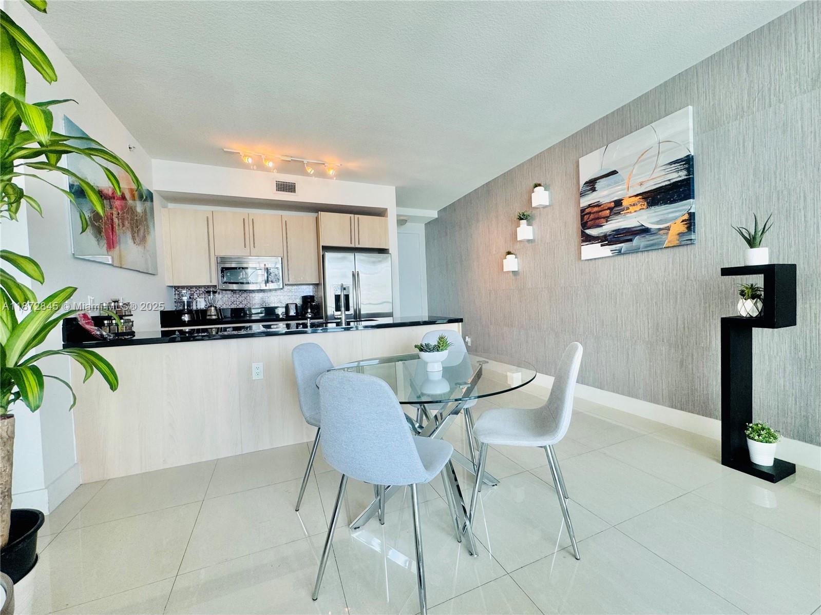 79 Southwest 12th Street, Unit 3211S Miami, FL 33130 - Photo 9 of 32 a kitchen with stainless steel appliances kitchen island granite countertop a sink and a refrigerator