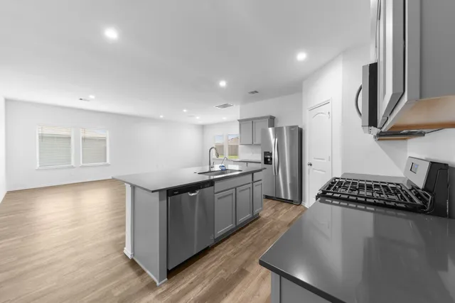 a kitchen with stainless steel appliances granite countertop a sink a stove and a refrigerator