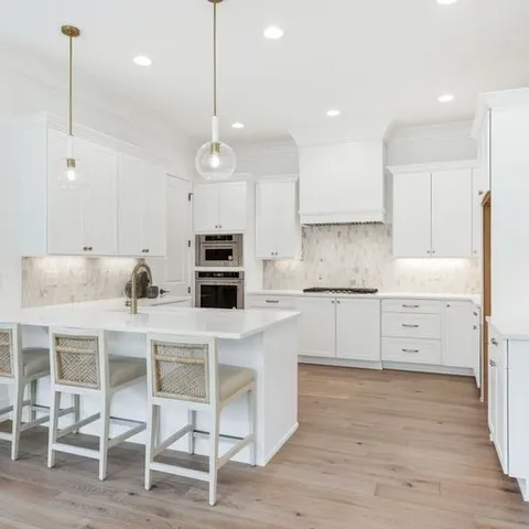 a kitchen with a stove a refrigerator and white cabinets