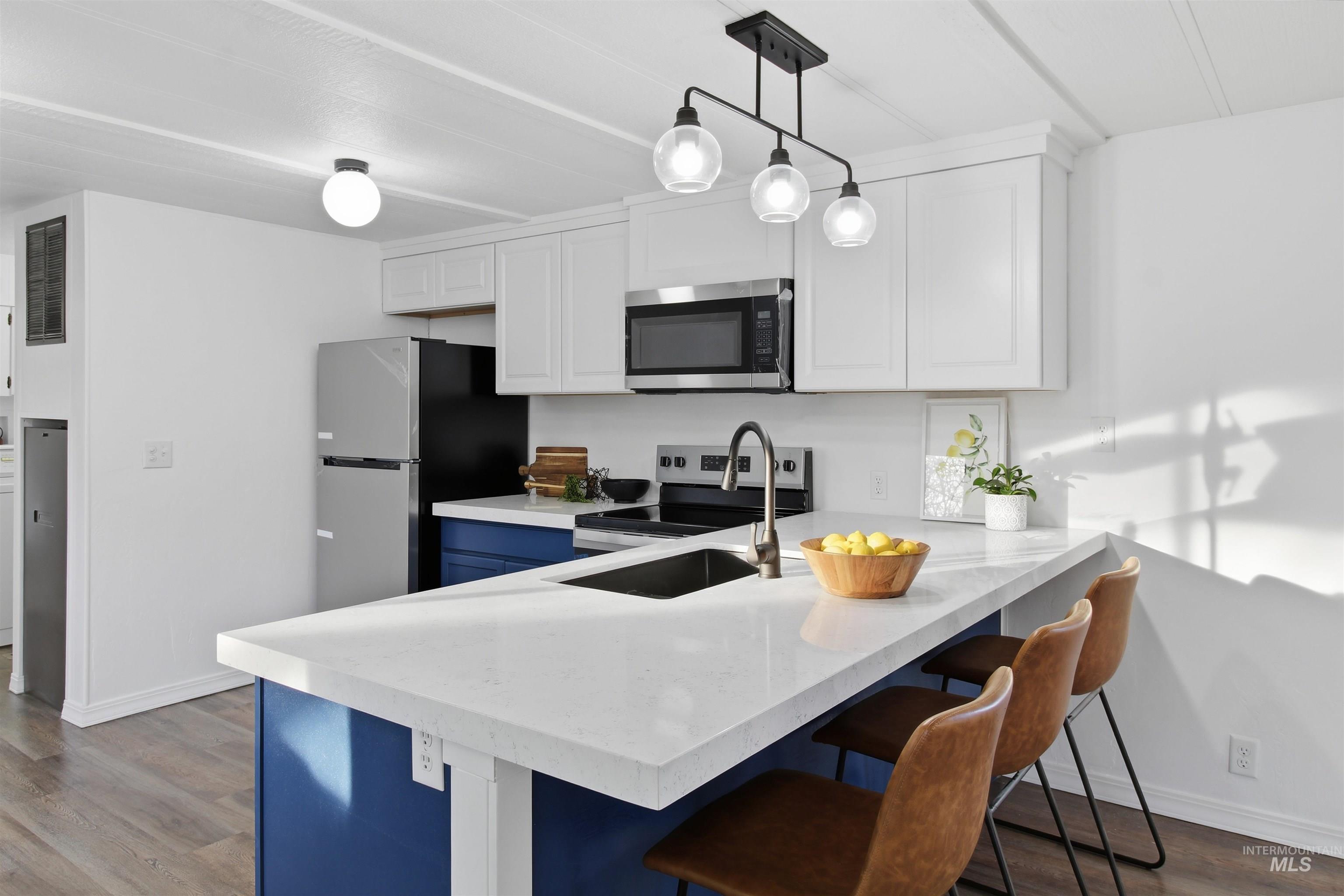198 South Hills Road, Unit 43 Twin Falls, ID 83301 - Photo 16 of 25 Kitchen with white cabinets, a breakfast bar, dark wood-type flooring, stainless steel appliances, and light stone countertops
