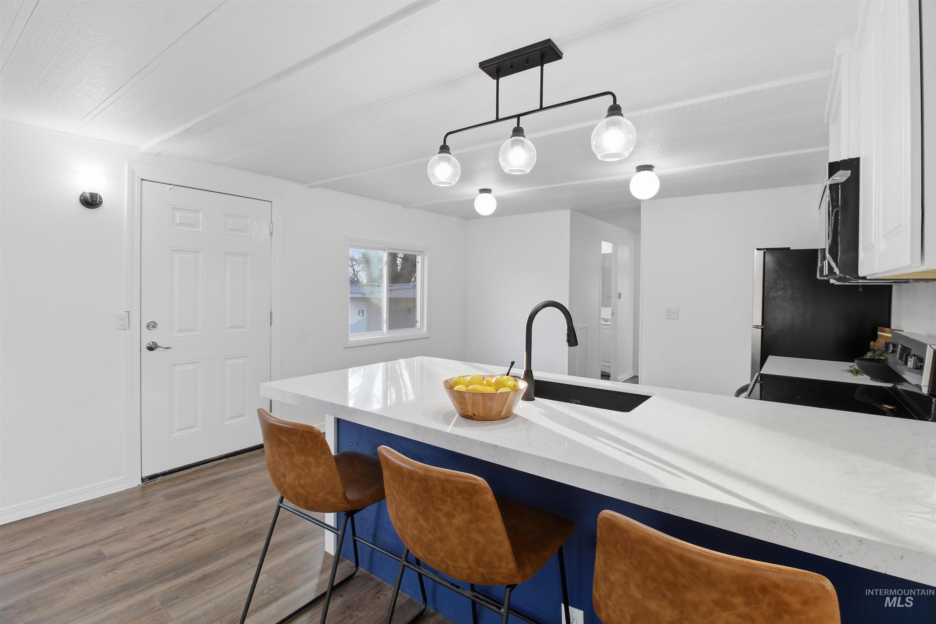 198 South Hills Road, Unit 43 Twin Falls, ID 83301 - Photo 2 of 25 Kitchen with a peninsula, a breakfast bar area, decorative light fixtures, dark wood finished floors, and black appliances
