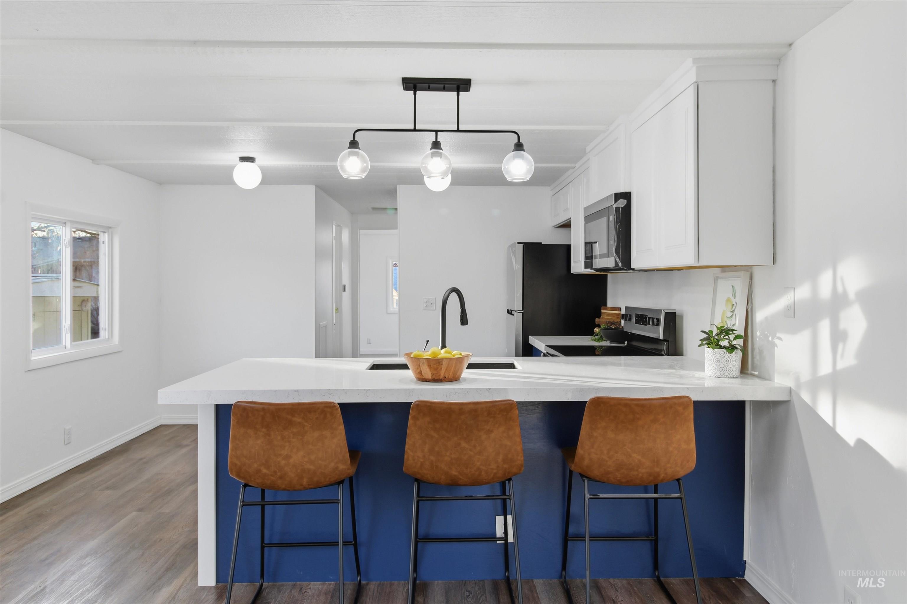 198 South Hills Road, Unit 43 Twin Falls, ID 83301 - Photo 3 of 25 Kitchen featuring a peninsula, a breakfast bar area, white cabinetry, dark wood-type flooring, and stainless steel appliances