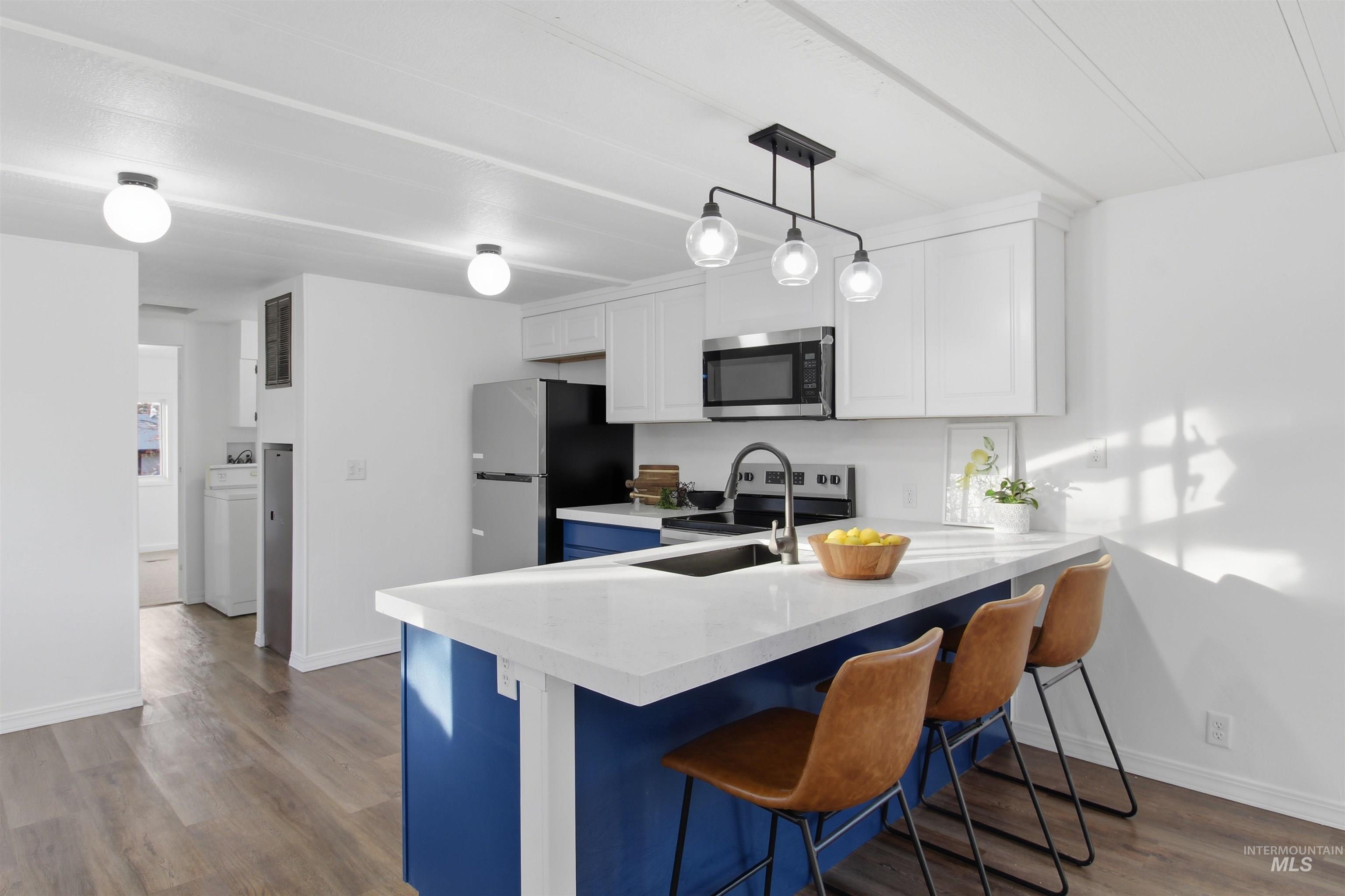 198 South Hills Road, Unit 43 Twin Falls, ID 83301 - Photo 5 of 25 Kitchen featuring a breakfast bar, white cabinetry, a peninsula, dark wood-style flooring, and hanging light fixtures