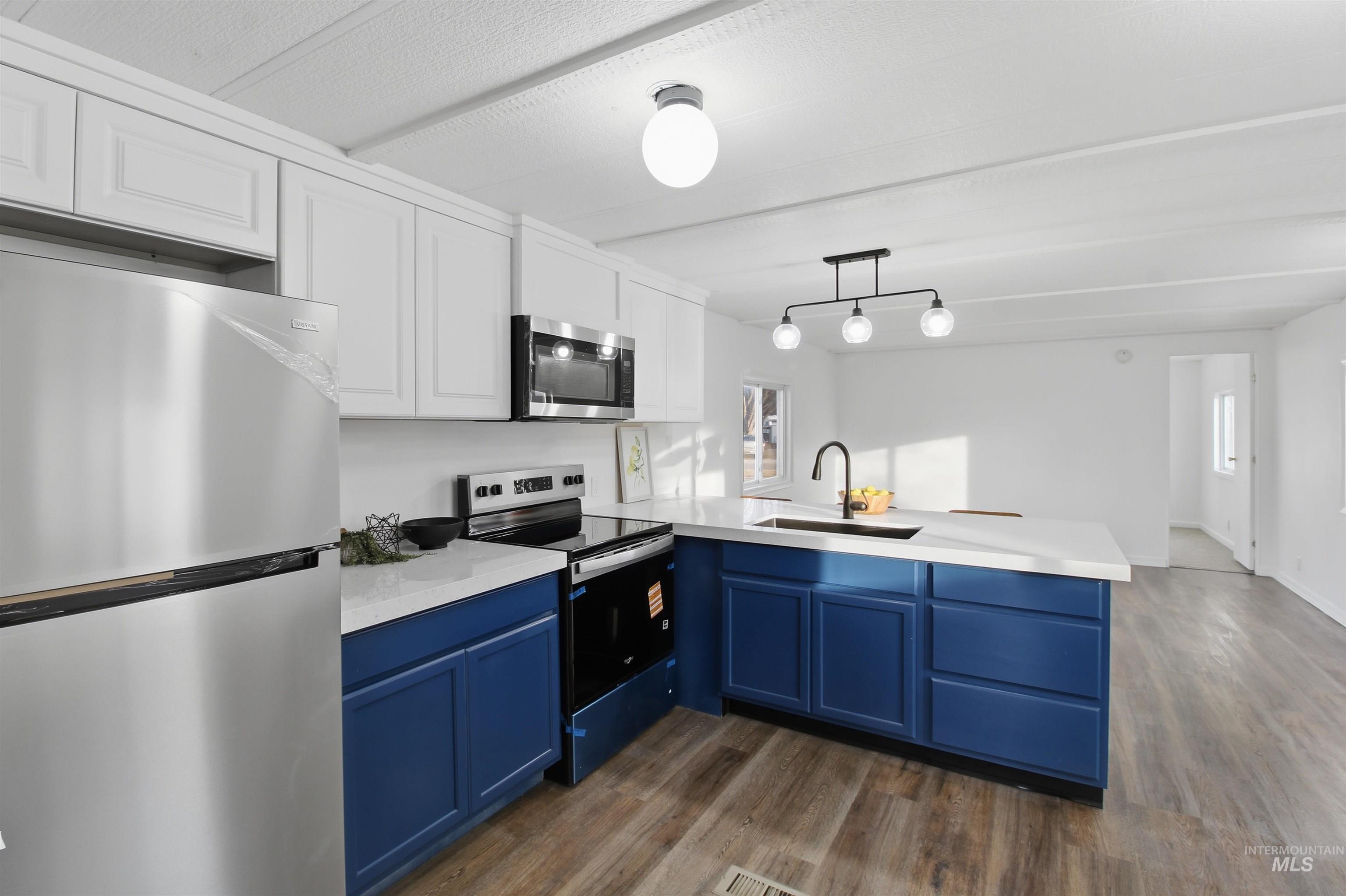 198 South Hills Road, Unit 43 Twin Falls, ID 83301 - Photo 7 of 25 Kitchen featuring appliances with stainless steel finishes, a peninsula, white cabinets, pendant lighting, and blue cabinets