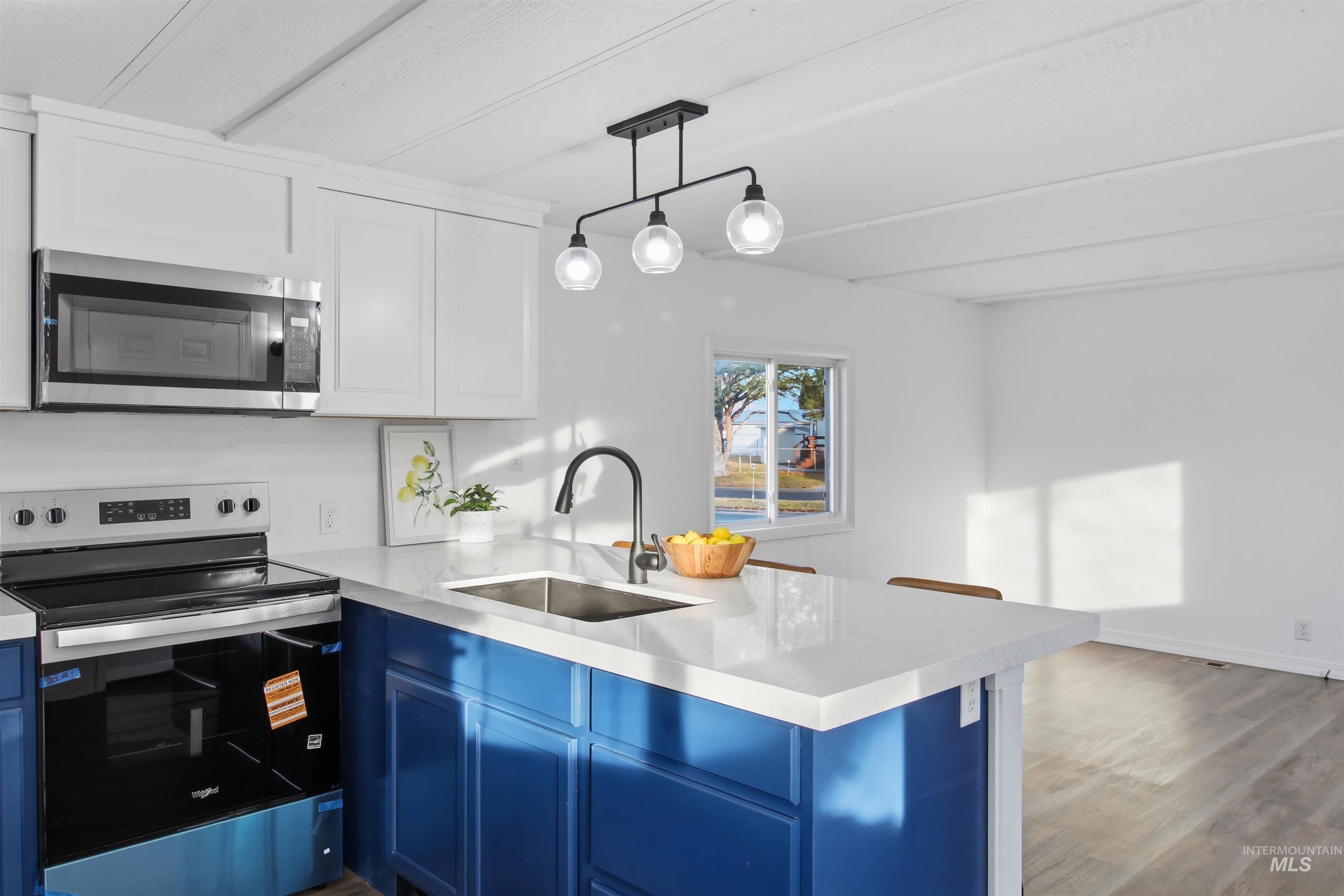 198 South Hills Road, Unit 43 Twin Falls, ID 83301 - Photo 8 of 25 Kitchen with stainless steel appliances, blue cabinets, pendant lighting, light wood-style floors, and white cabinetry