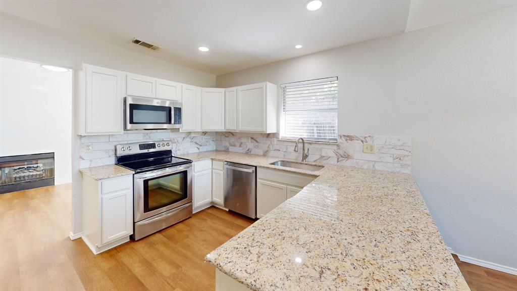 7913 Rice Drive Rowlett, TX 75088 - Photo 5 of 25 Kitchen featuring light wood-finish flooring, white cabinetry, and granite countertops