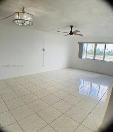 an empty room with chandelier fan and windows
