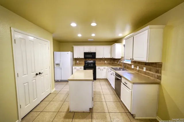 a large kitchen with stainless steel appliances granite countertop a refrigerator and a stove top oven