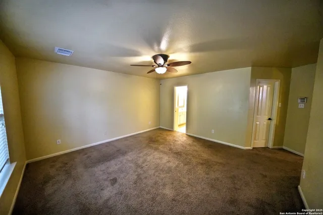 an empty room with a ceiling fan and a window