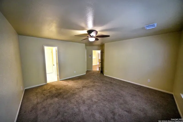 an empty room with windows and ceiling fan