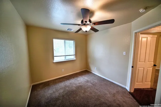 an empty room with windows and fan