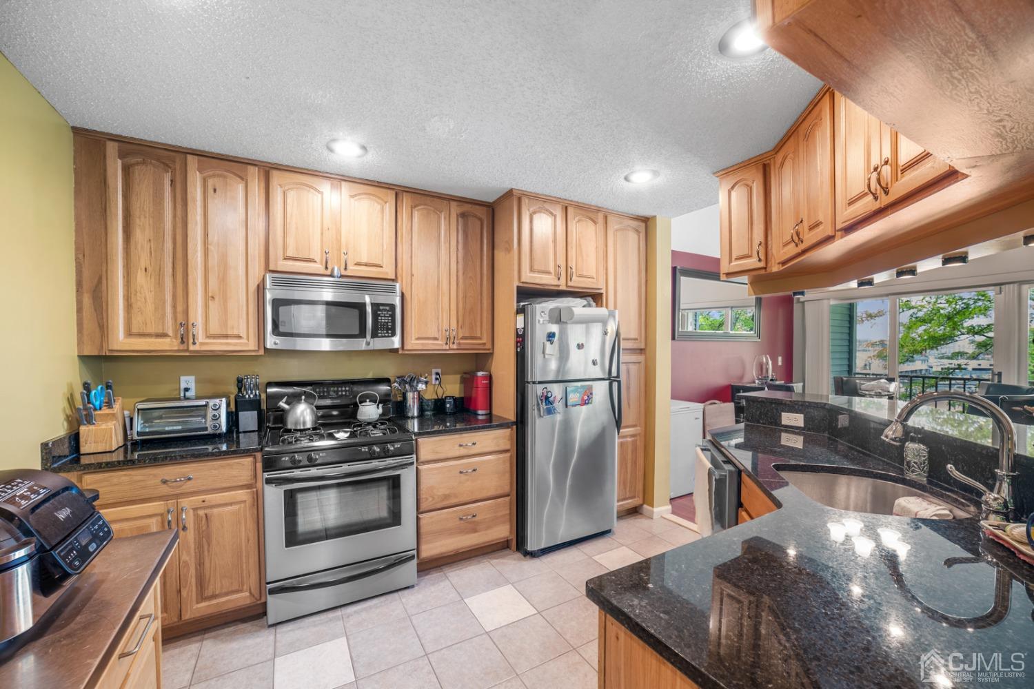 133 Edpas Road New Brunswick, NJ 08901 - Photo 7 of 17 a kitchen with stainless steel appliances granite countertop a stove a sink a refrigerator and blue cabinets with wooden floor