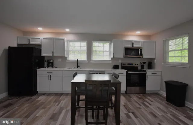 a kitchen with a refrigerator a stove a sink a dining table and chairs