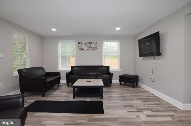 a kitchen with stainless steel appliances a microwave a sink a stove a refrigerator white cabinets and wooden floor