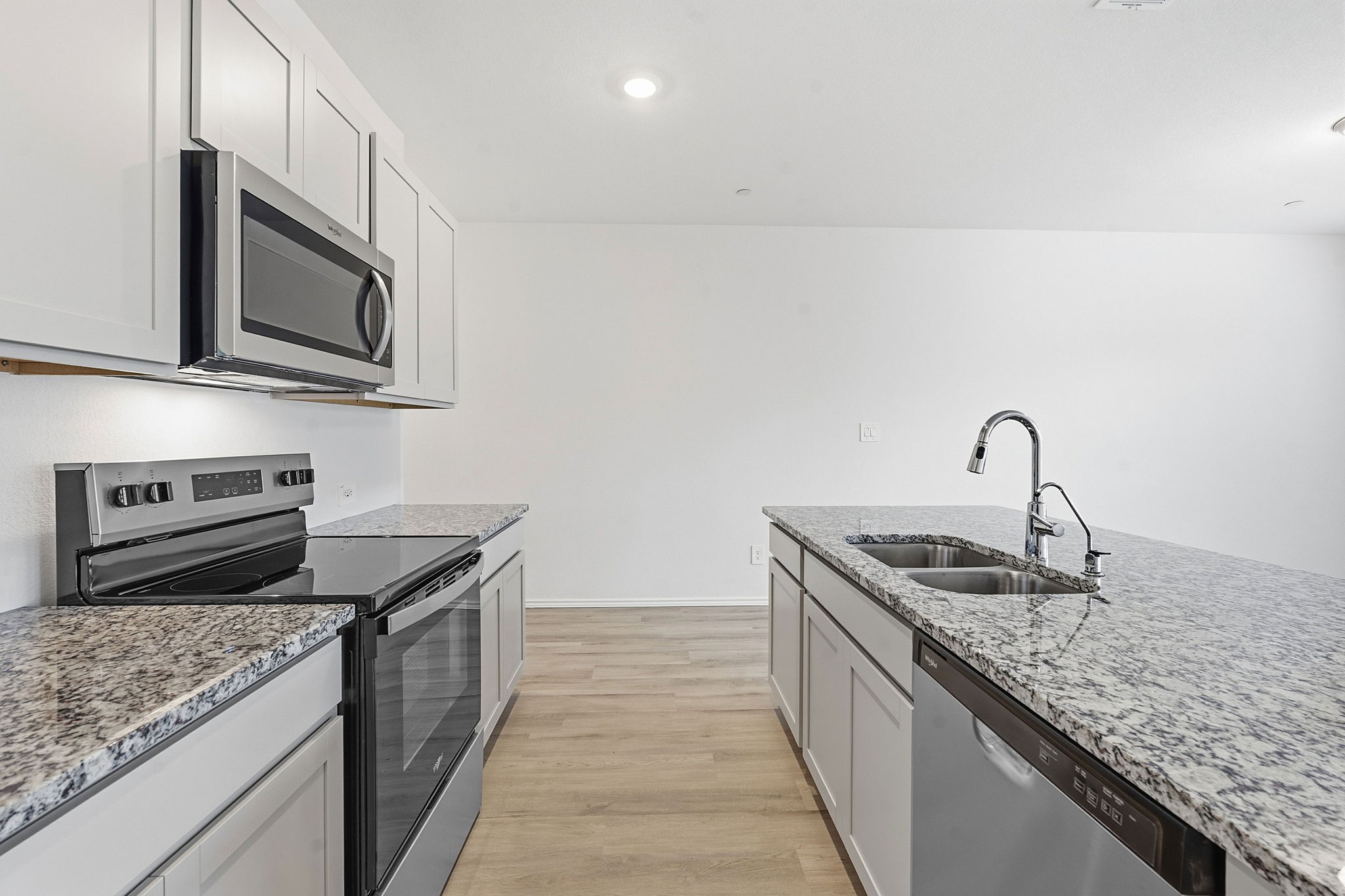 164 Cinnabar Lane, Unit 3 Kyle, TX 78640 - Photo 8 of 20 Modern kitchen featuring light cabinetry, stainless steel appliances, speckled stone countertops, and wood-finish flooring