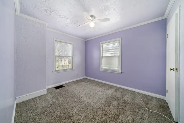 an empty room with windows and ceiling fan