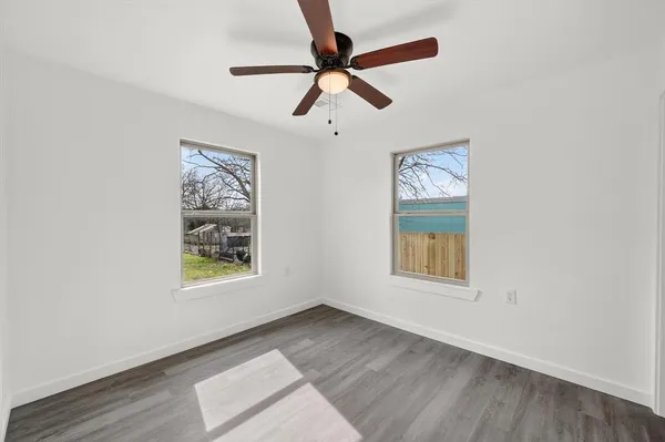 an empty room with windows and fan