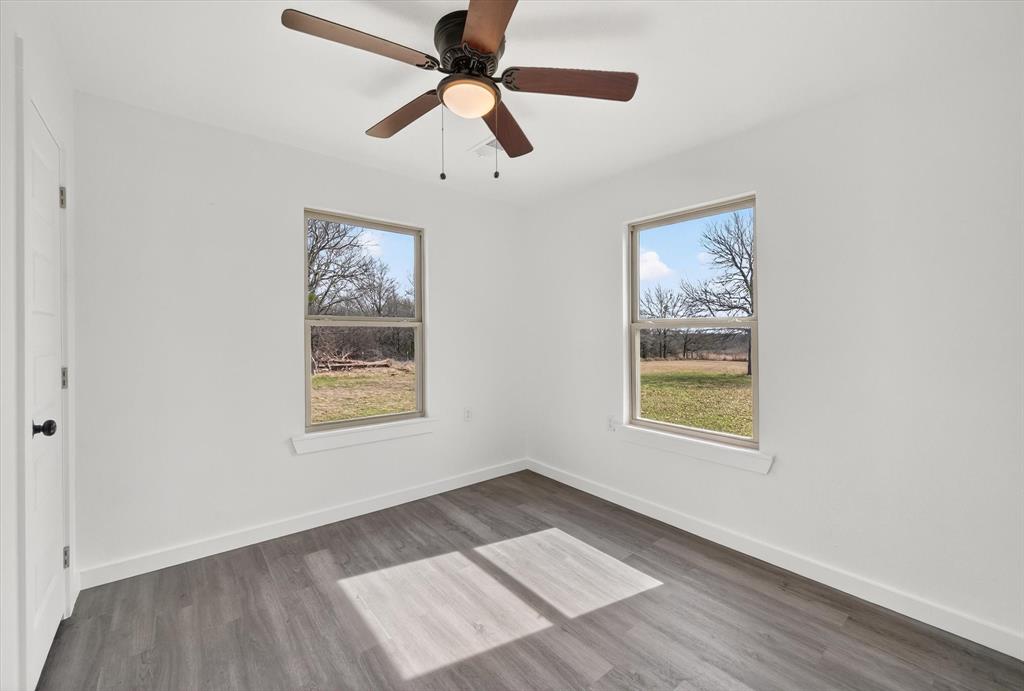 705 South 3rd Street East Dawson, TX 76639 - Photo 19 of 25 an empty room with wooden floor ceiling fan and windows