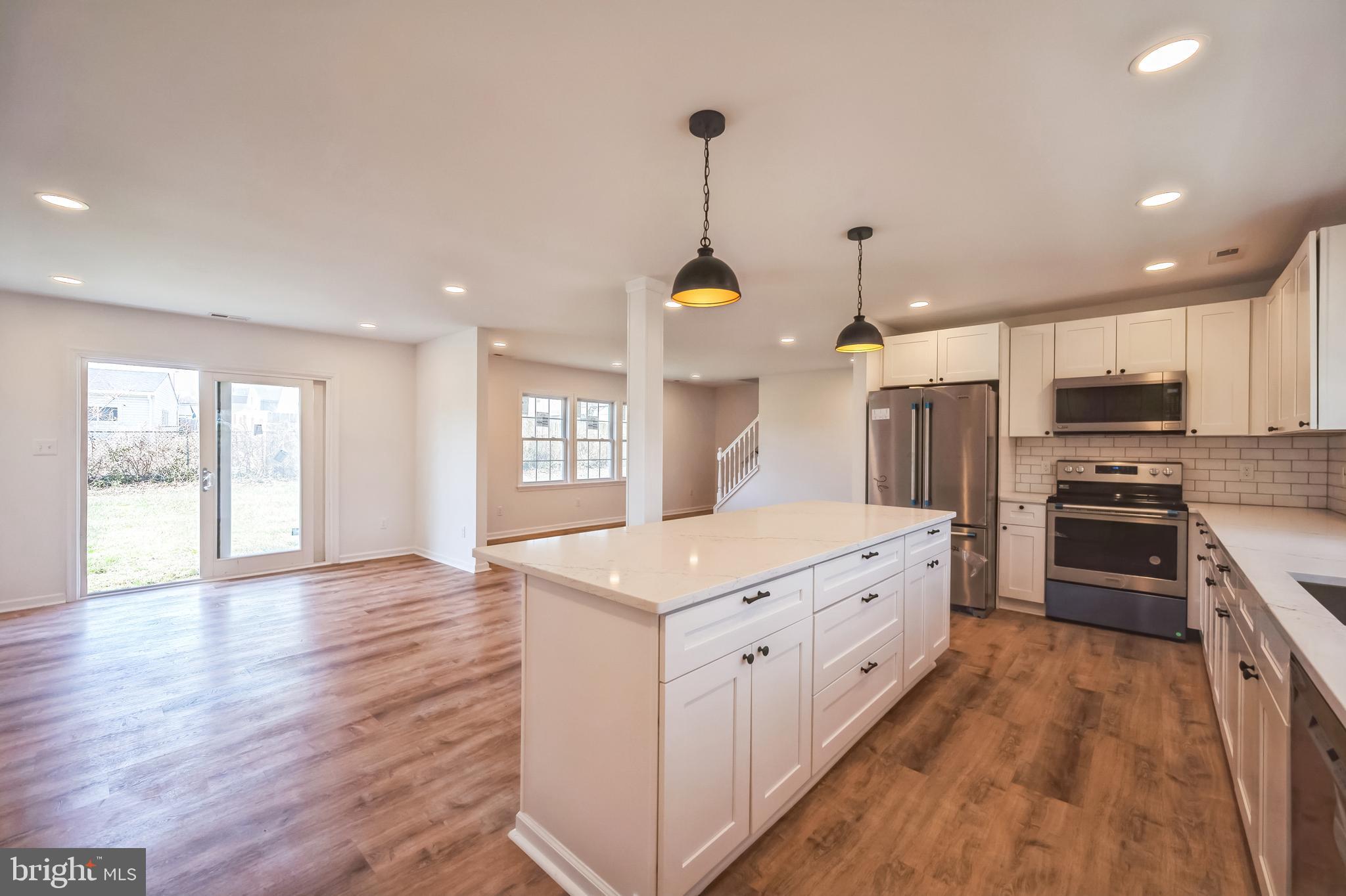 5 River Lane Levittown, PA 19055 - Photo 25 of 35 a large kitchen with stainless steel appliances kitchen island granite countertop a stove a sink a refrigerator and a wooden floor