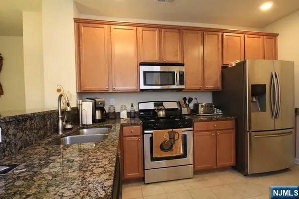 a kitchen with granite countertop a refrigerator stove and microwave