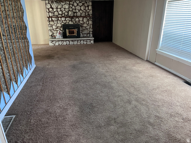 1766 Pine Rd Pine Canyon Tooele, UT 84074 - Photo 12 of 16 Living area featuring wall-to-wall carpeting, a built-in stone fireplace, and window with horizontal blinds