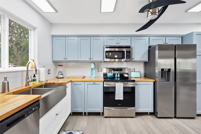 a kitchen with a sink a counter top space stainless steel appliances and a window